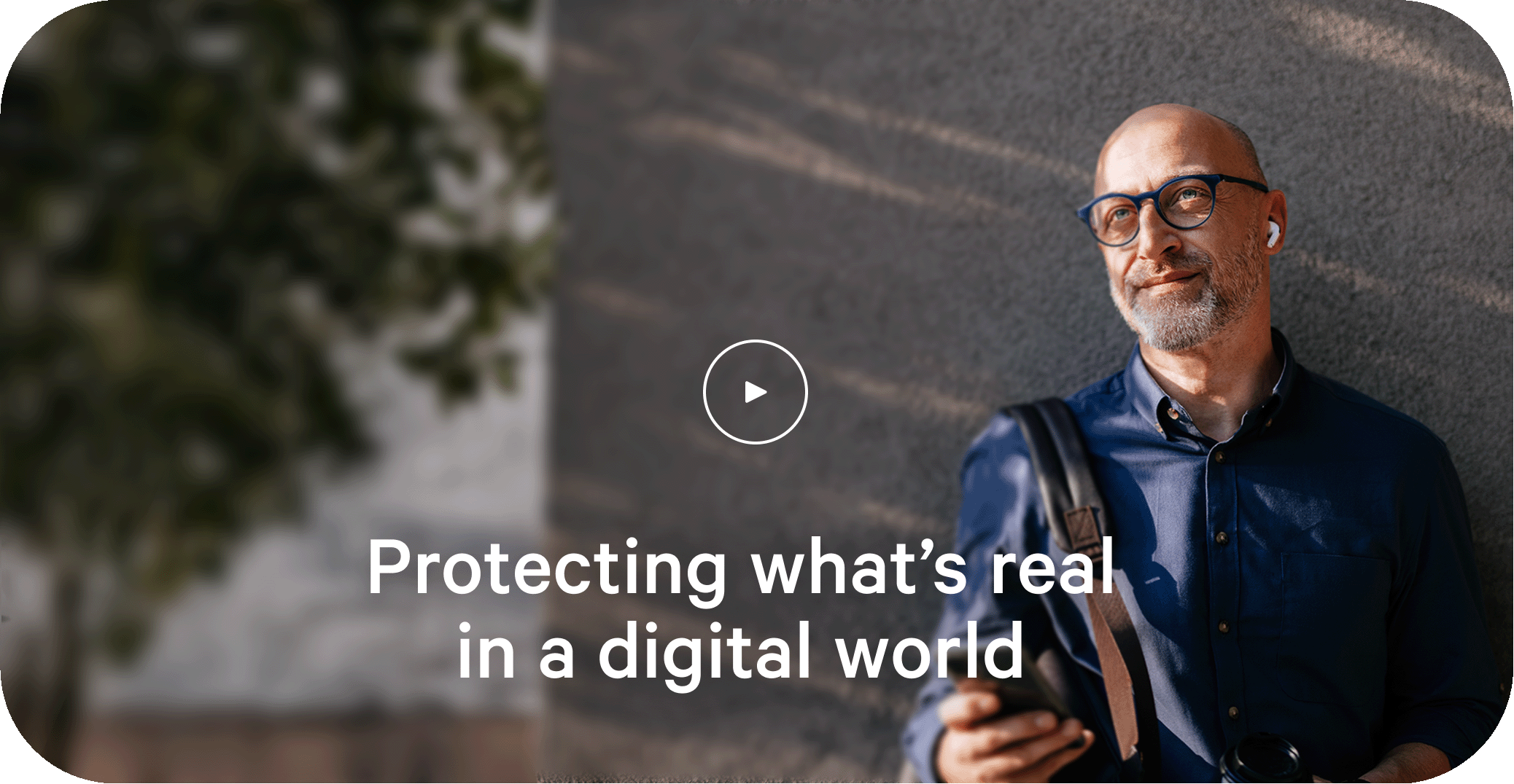 Man leaning against wall outside with mobile device in hand